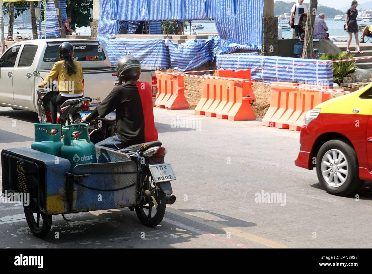 Pattaya, Thailand - December 24, 2019: Man transports a gas bottles with motorcycle on Beach Road. Stock Photo