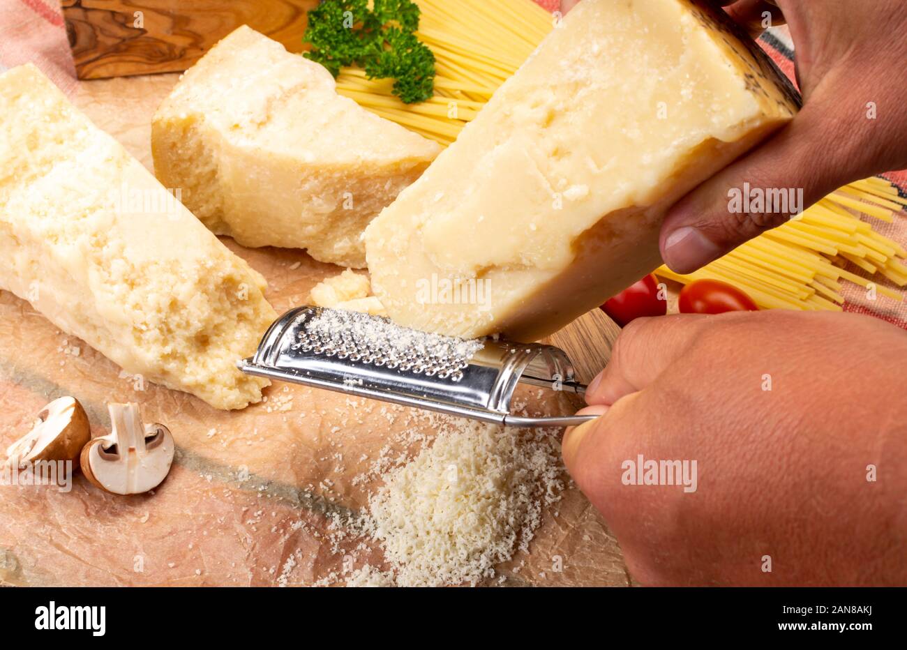 https://c8.alamy.com/comp/2AN8AKJ/man-cooking-with-hard-italian-cheese-grated-parmesan-or-grana-padano-cheese-hand-with-cheese-grater-2AN8AKJ.jpg