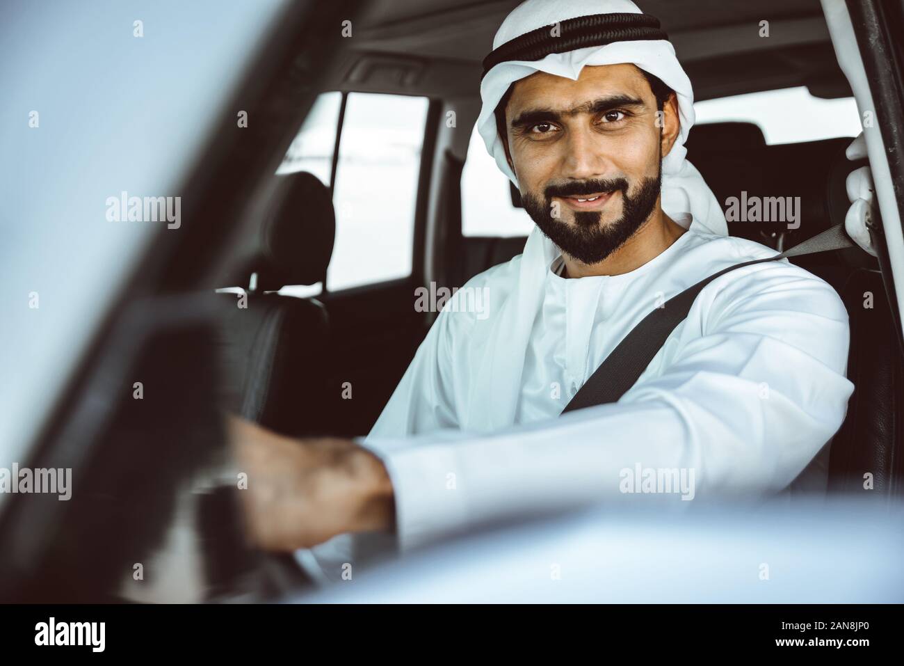 Handsome man with uae traditional outfit driving in Dubai. Middle