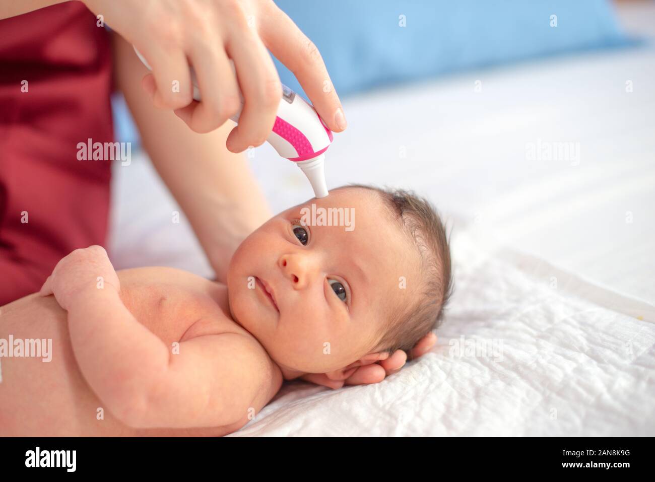 Doctor with digital thermometer checking newborn temperature Stock Photo