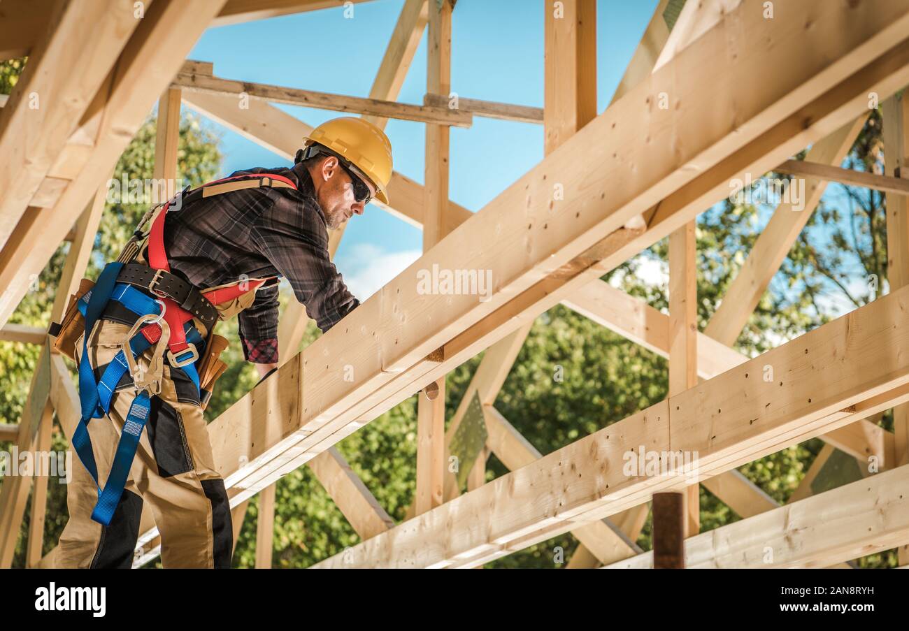 Wood House Frame Construction. Industrial Theme. Caucasian Contractor Worker. Stock Photo