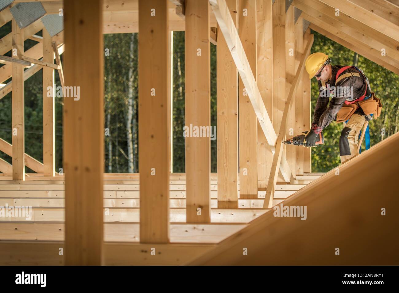 Wood Skeleton Frame Job. Professional Construction Worker with Nail Gun. Industrial Theme. Stock Photo