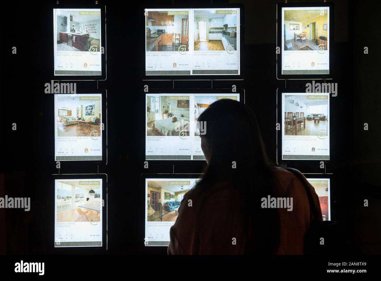 A woman looks at the housing offerings at an American real estate agent franchise, Century 21 Real Estate, seen in Spain. Stock Photo