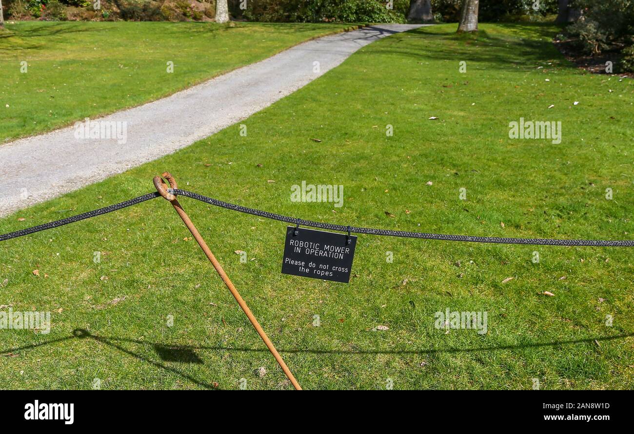 A sign in the garden saying 'Robotic mower in operation' at Bodnant Gardens, Tal-y-Cafn, Conwy, Wales, UK Stock Photo