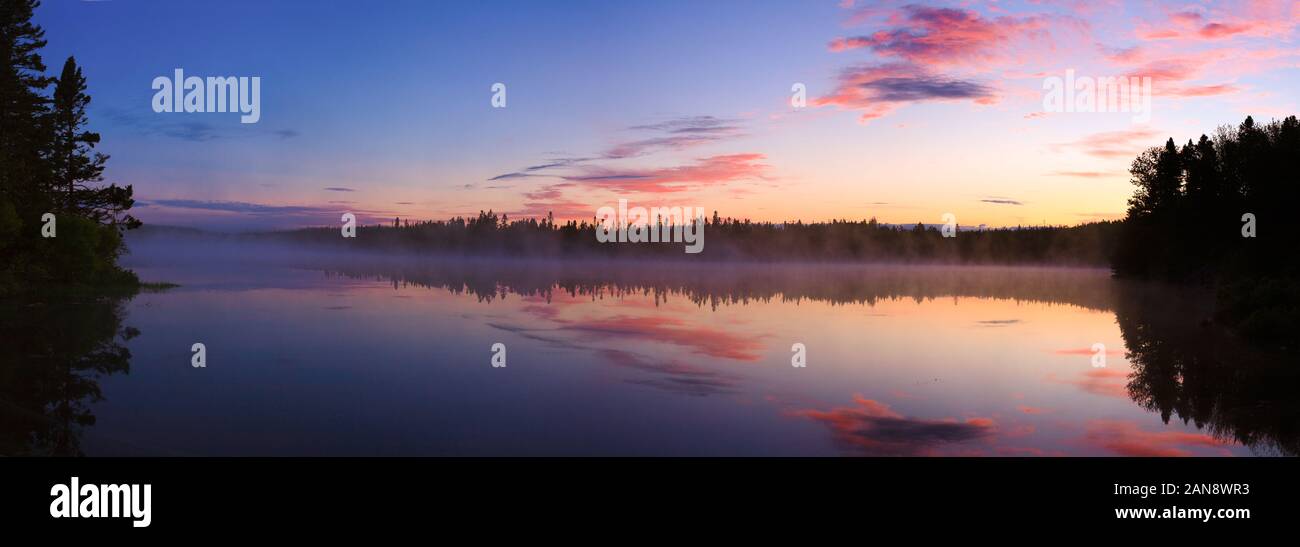 Daybreak reflections on a calm lake. Wide format image. Stock Photo