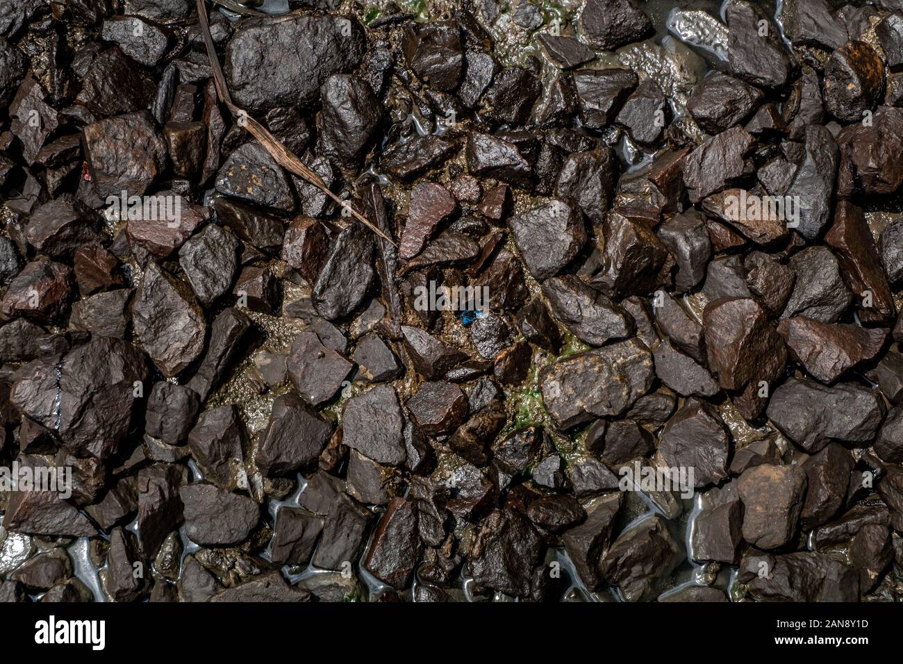 Ballast stone gravel soaked with engine oil in the railroad tracks