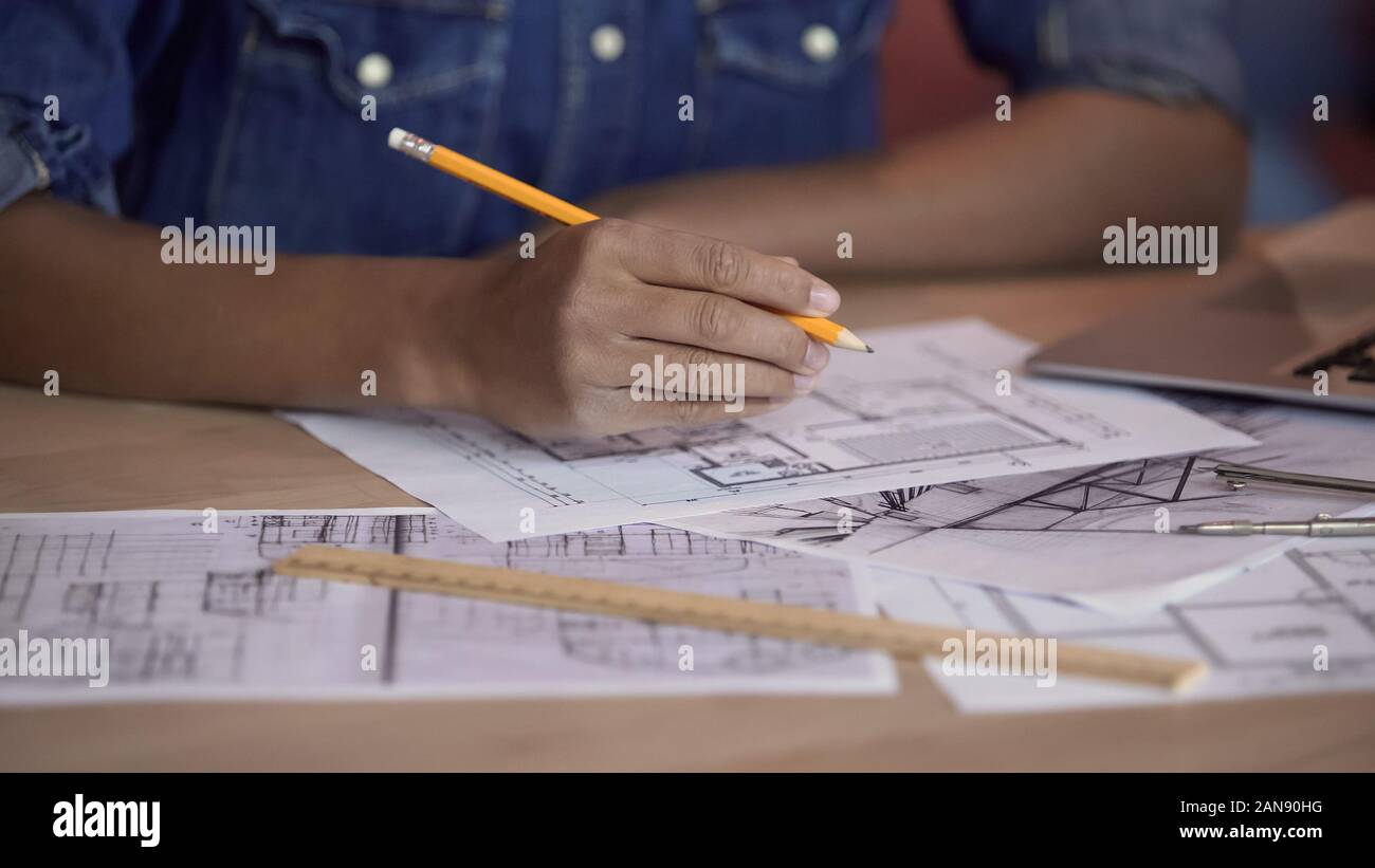 Mixed-race designer working on apartment layout plan, holding pencil, project Stock Photo