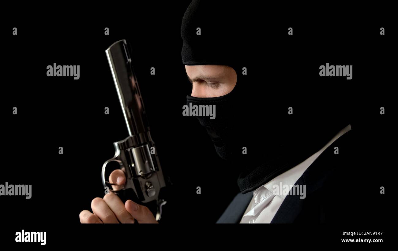 Killer in balaclava holding gun, preparing for armed robbery, bank break in Stock Photo