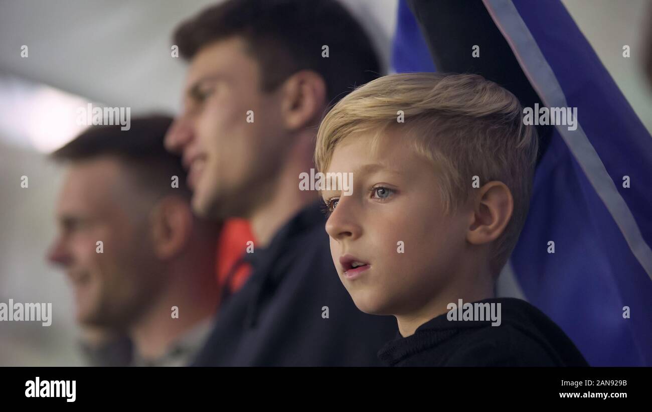 Child and adult fans with national flag, cheering for football team at