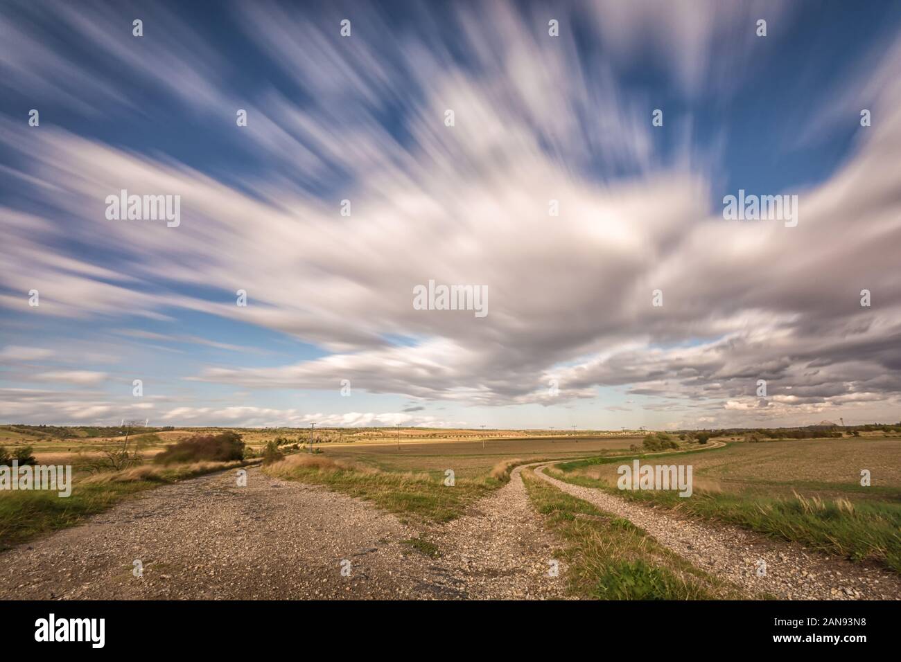 Rural region with two dirt roads and fast passing clouds Stock Photo