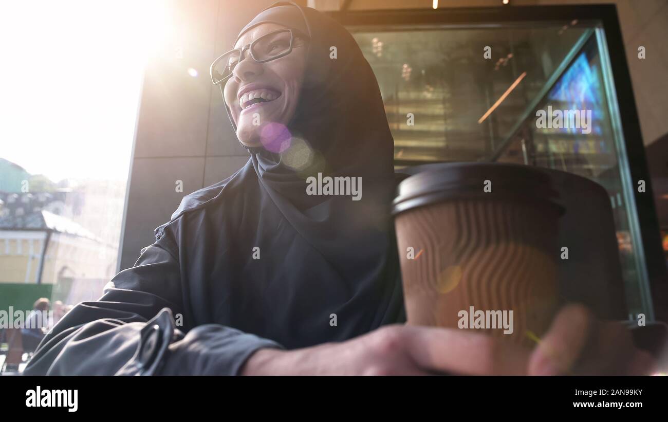 Happy muslim female holding cup of coffee, relaxing in bistro, modern lifestyle Stock Photo