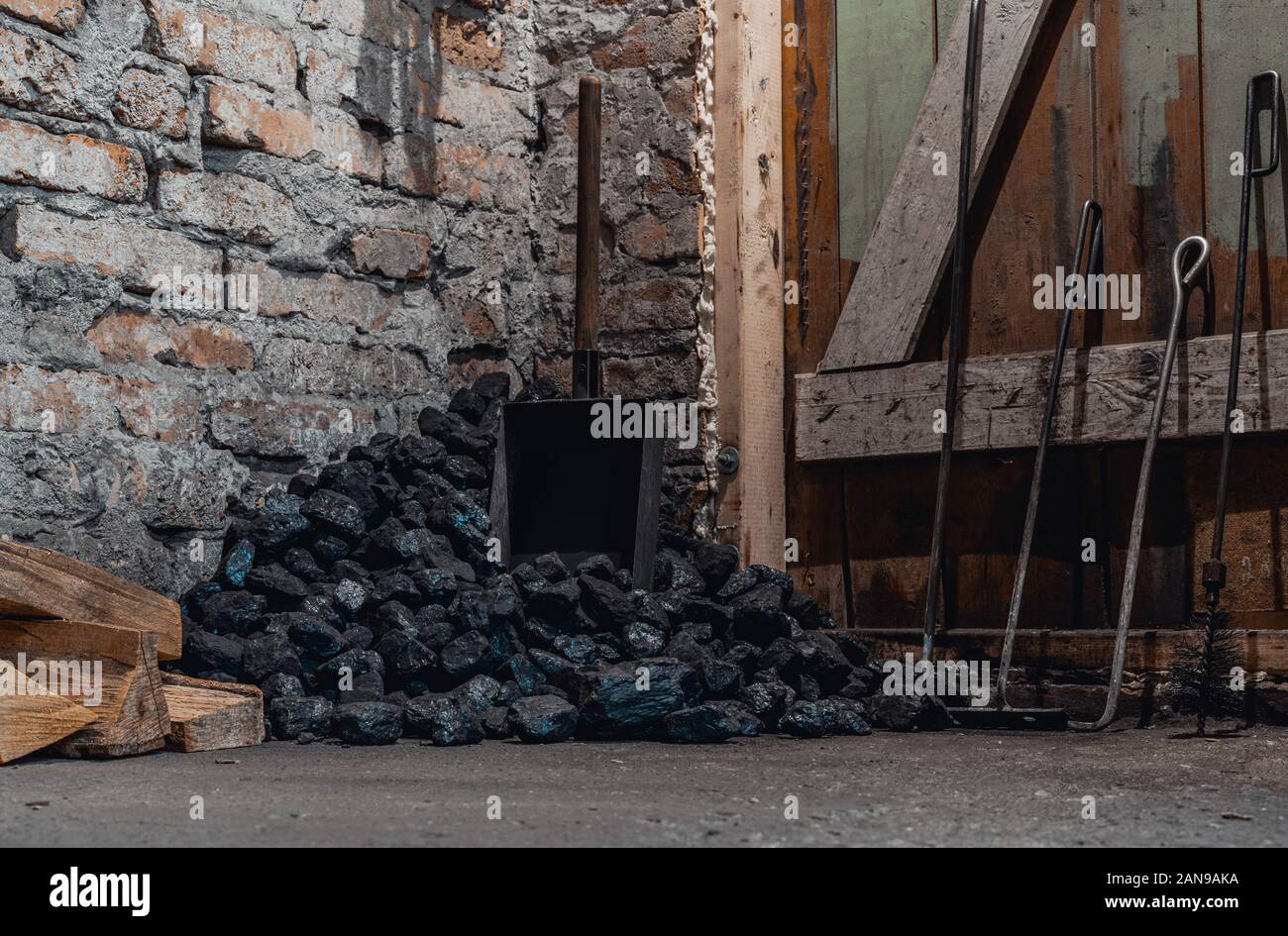 Coal, wood and shovel on the floor at the basement prepared for heating the house with. Stock Photo