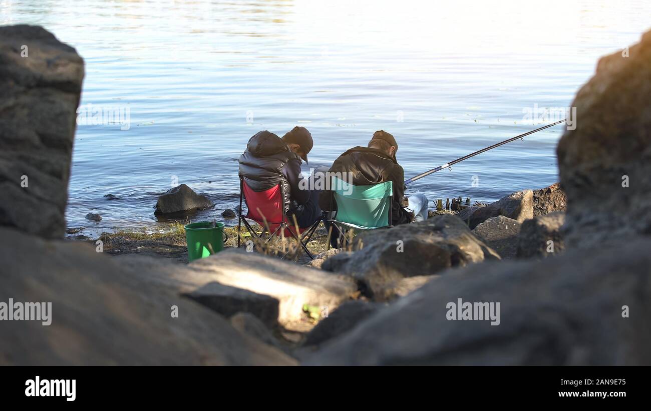 Drunk males falling asleep while fishing, tiring leisure activity, exhaustion Stock Photo