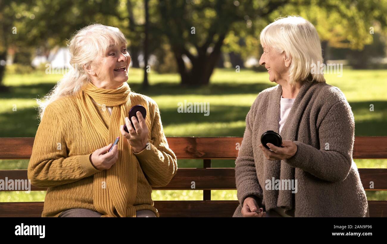 Funny mature women making-up lips and looking to each other, fashion for elder Stock Photo