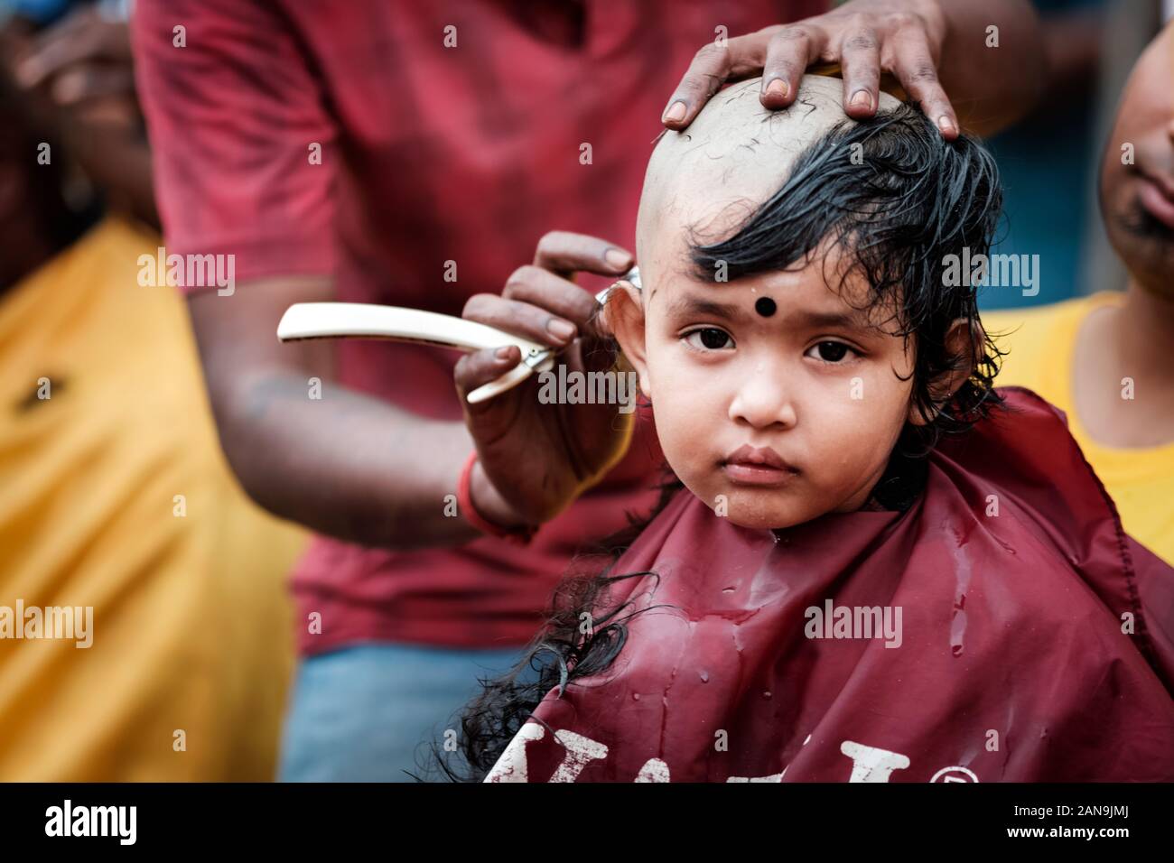 Batu Caves, Malaysia - January 21 2019 : Close-up of baby boy devotee getting tonsured or head shaving ritual in Thaipusam Festival. Stock Photo