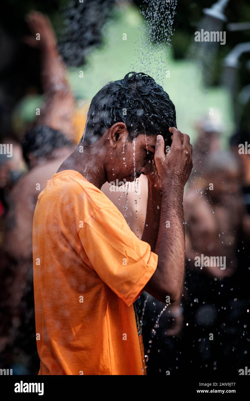 Batu Caves, Malaysia - January 21 2019 : Close-up of young boy devotee having shower ritual in Thaipusam Festival. Stock Photo