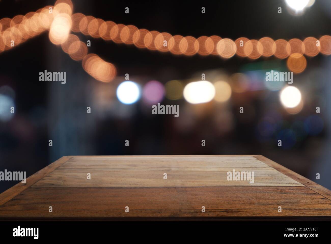 Empty wooden table in front of abstract blurred night light in cafe ...