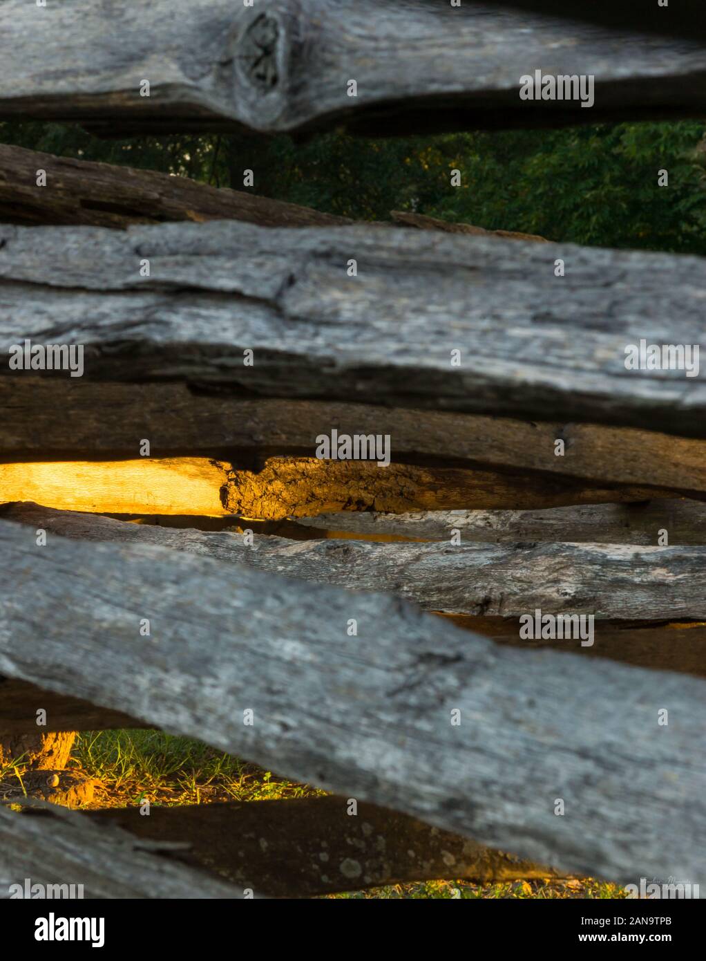 A split-rail fence or log fence (also known as a zigzag fence, worm fence or snake fence historically due to its meandering layout) is a type of fence Stock Photo