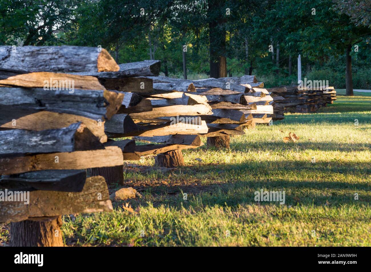 A split-rail fence or log fence (also known as a zigzag fence, worm fence or snake fence historically due to its meandering layout) is a type of fence Stock Photo