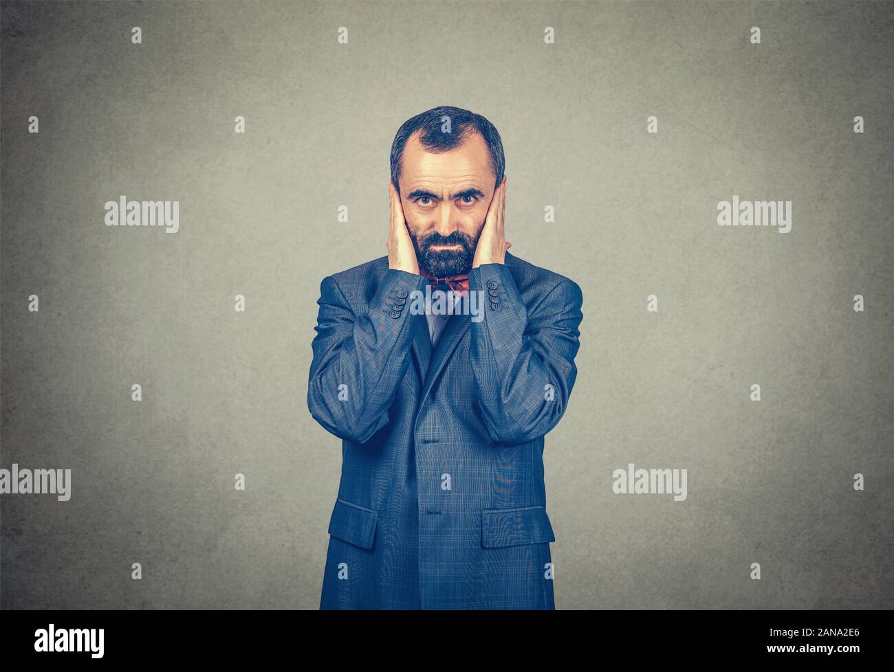 Man hands on ears with calm face expression. Hear no evil concept. Mixed race bearded model isolated on gray studio wall background with copy space. H Stock Photo