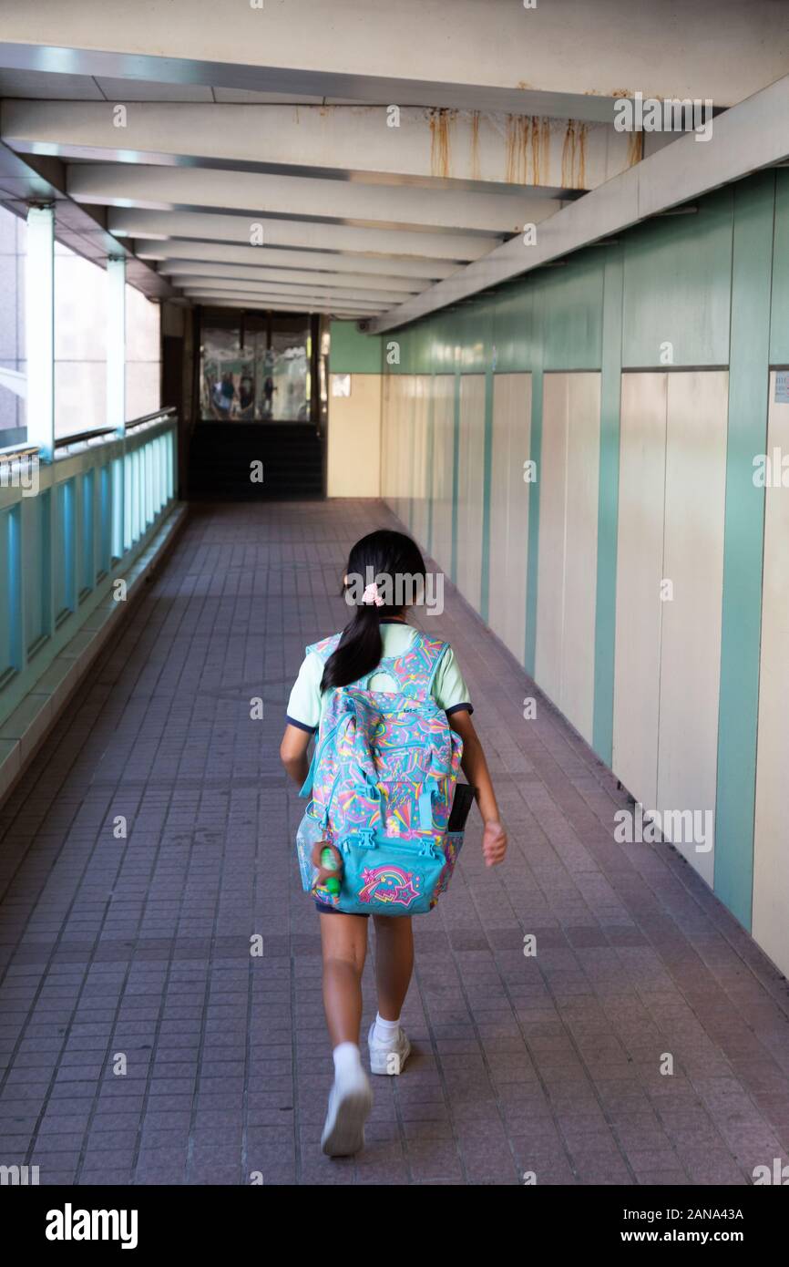 Hong Kong children - a schoolgirl aged 10 years rushing to school in the morning with her rucksack on her back, Hong Kong Asia Stock Photo