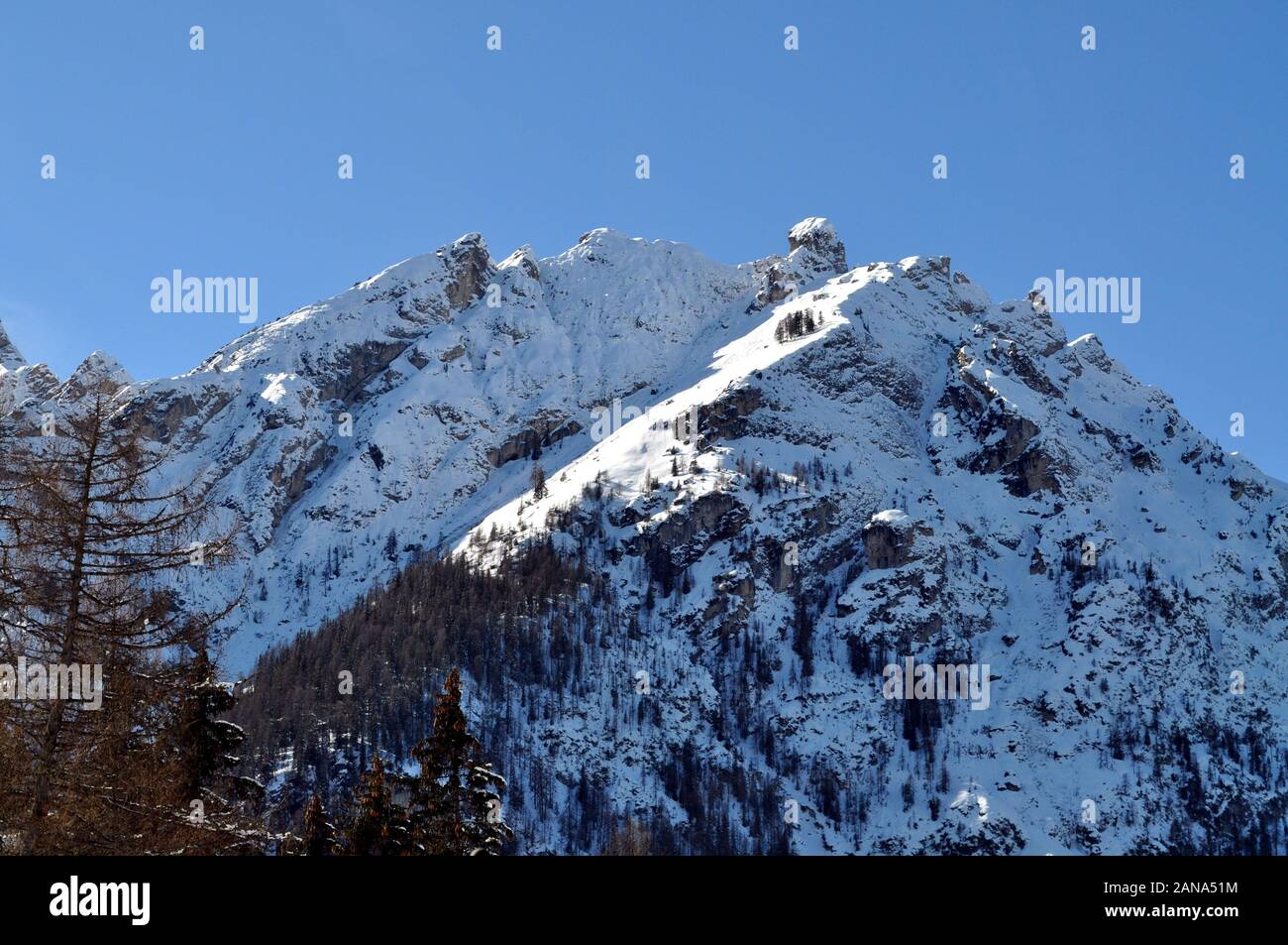 The snowcovered peak of the mountains is illuminated by the rays of the sun Stock Photo Alamy