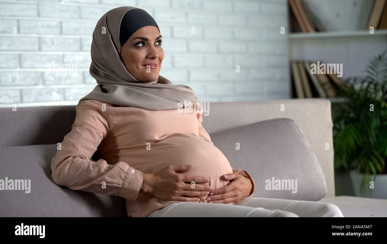 Pregnant muslim lady holding belly, guessing gender of unborn child