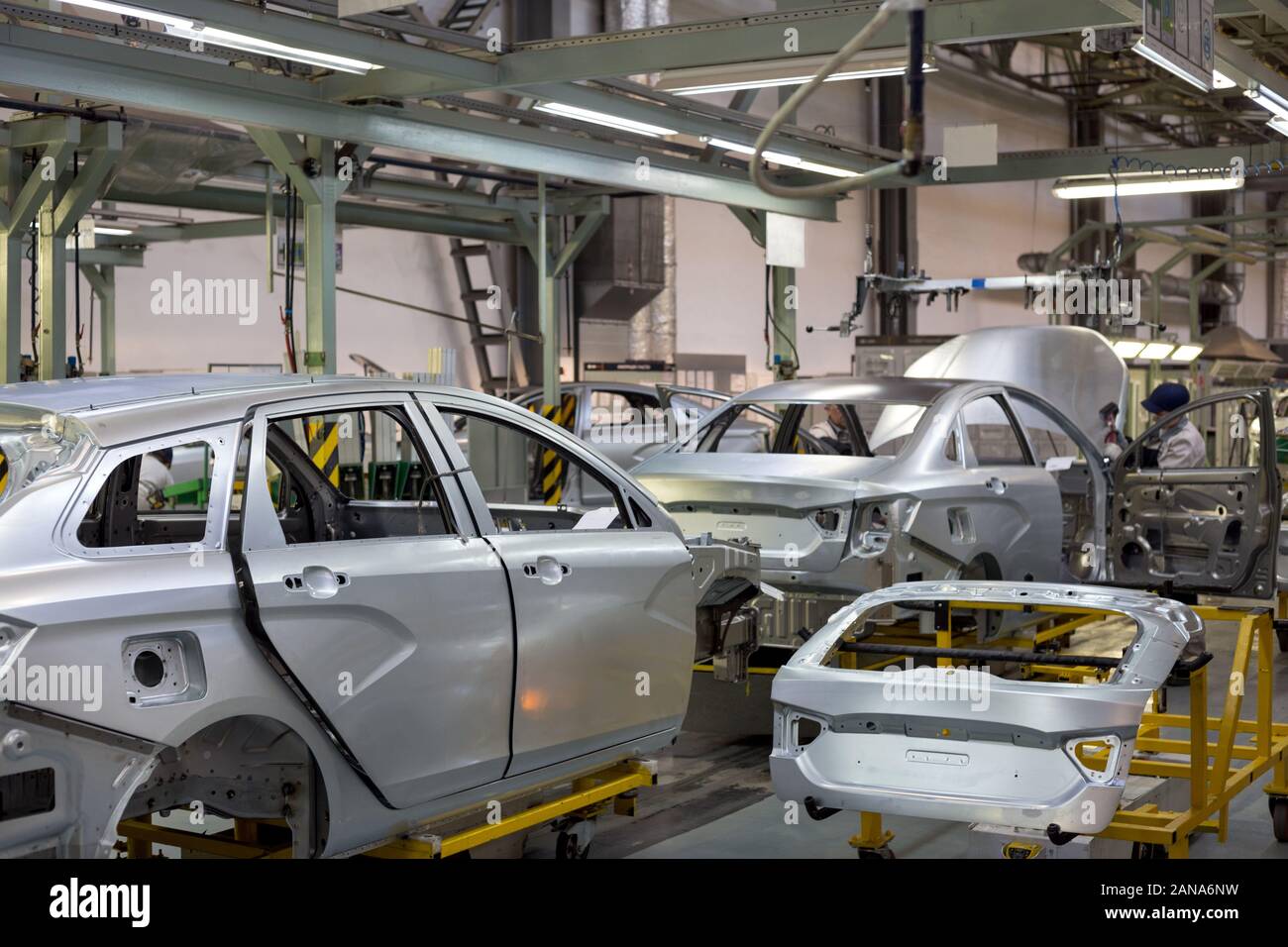 Russia, Izhevsk - December 14, 2019: LADA Automobile Plant Izhevsk, part of the AVTOVAZ Group. The worker is setting motor hood on a new car. Stock Photo