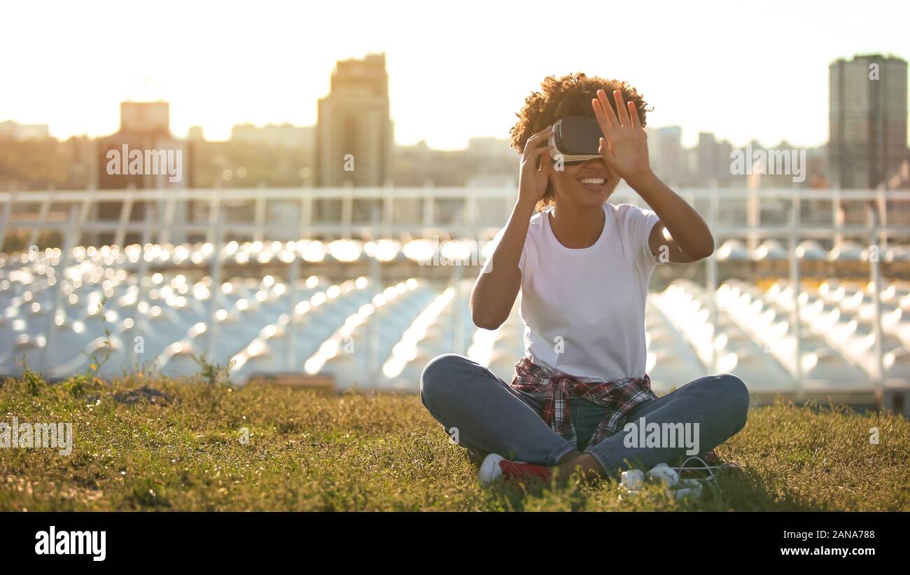 Curly haired lady using virtual reality glasses, touching air, modern technology Stock Photo