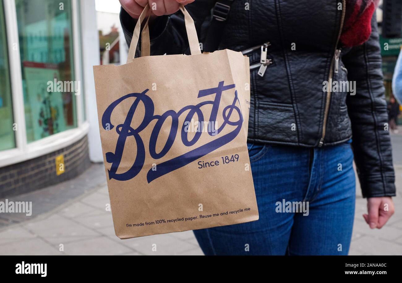 Young woman carrying a Boots the Chemist paper shopping bag UK Stock Photo