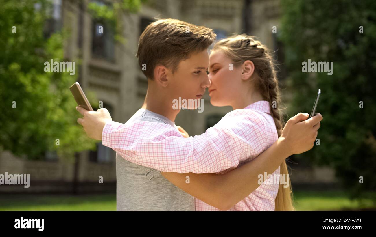 Couple using phone while hugging, addiction to social networking concept Stock Photo