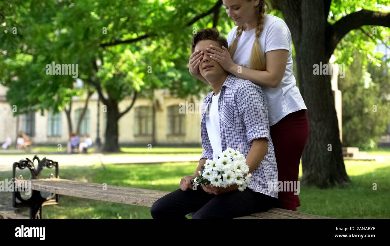 Girlfriend closing boyfriends eyes to guess who, romantic relationship, date Stock Photo