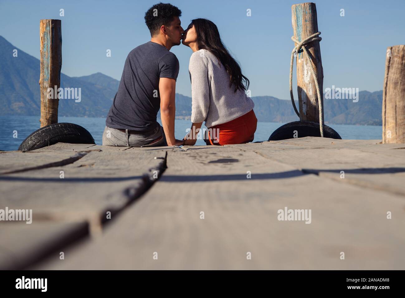 Couple sitting on the pier of Lake Atitlan in Guatemala seeing each other Stock Photo