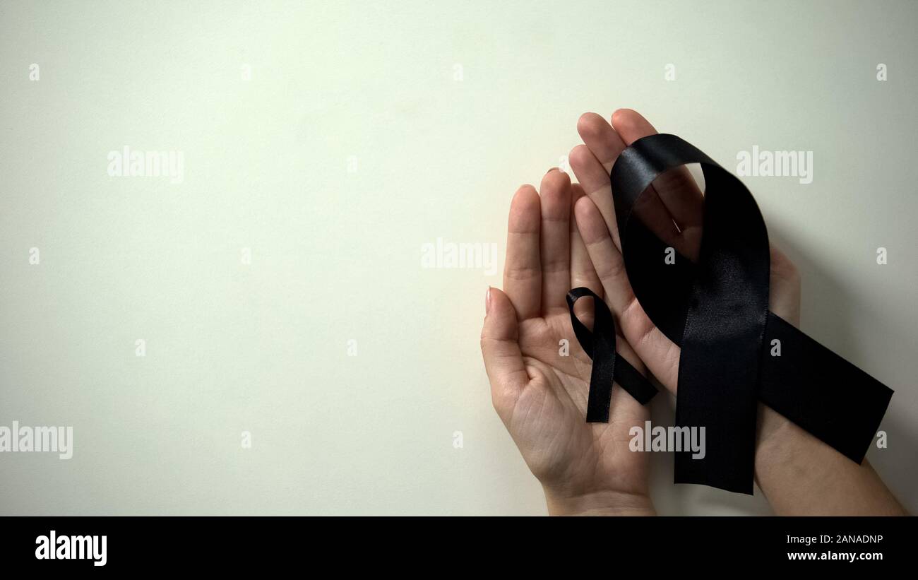 Big and little black ribbons in hands, melanoma awareness, skin cancer ...