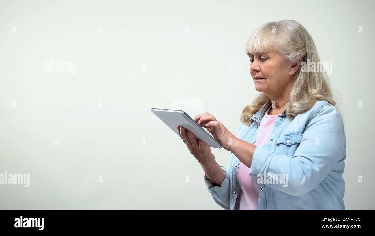 Aged woman using application on tablet for online shopping, modern technologies Stock Photo