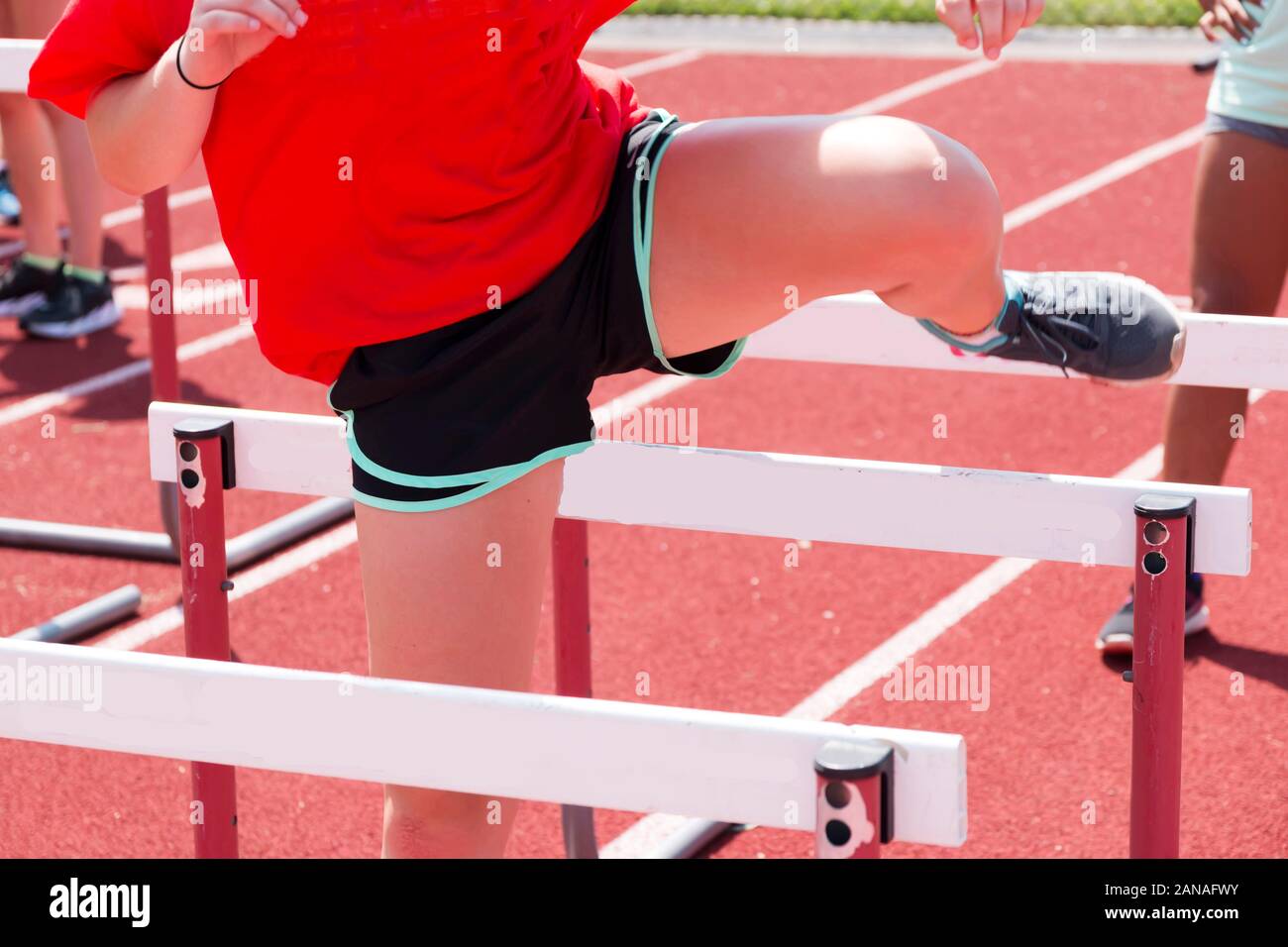 High school girls doing hurdle drills, working on her trail leg, at track and field practice Stock Photo