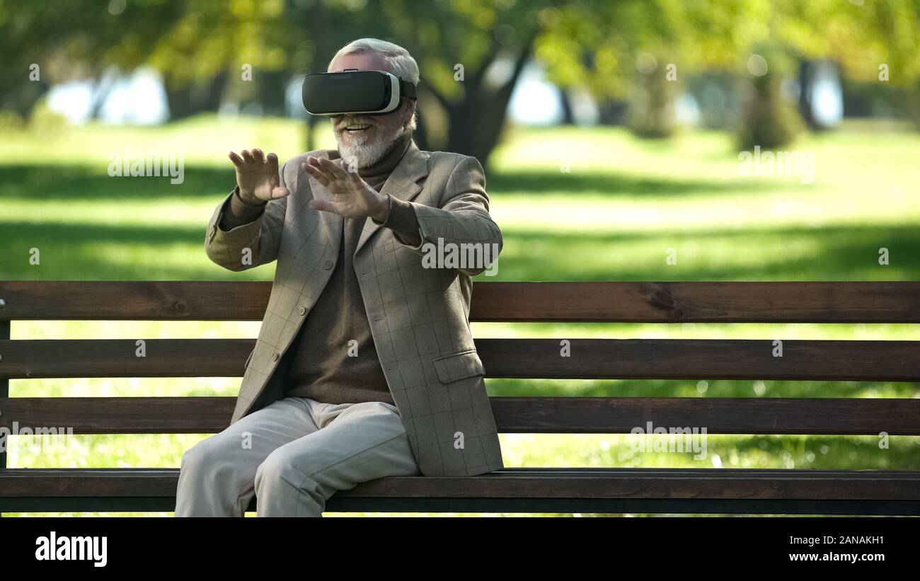 Amazed senior men using VR headset outdoors, modern technologies experience Stock Photo