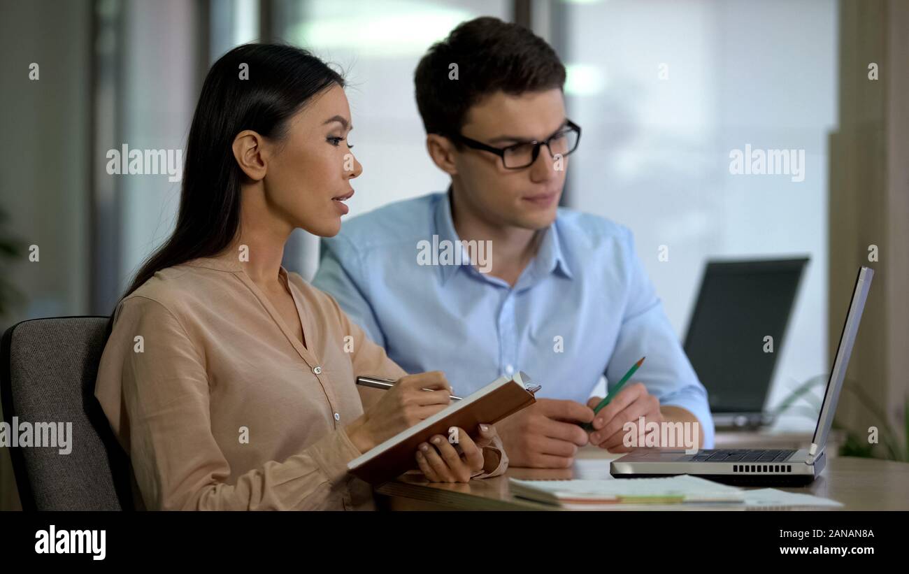 Young colleagues watching online training laptop making notes, planning strategy Stock Photo