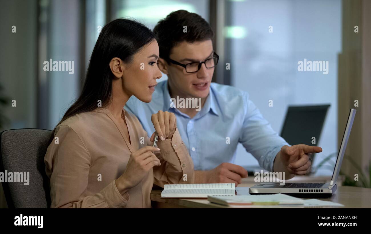 Professional crisis managers sitting front laptop, discussing company strategy Stock Photo