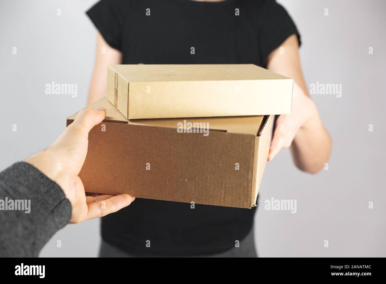 Taking or giving boxes with goods. Delivery, postal service or mailman concept: giving package from hand to hand Stock Photo
