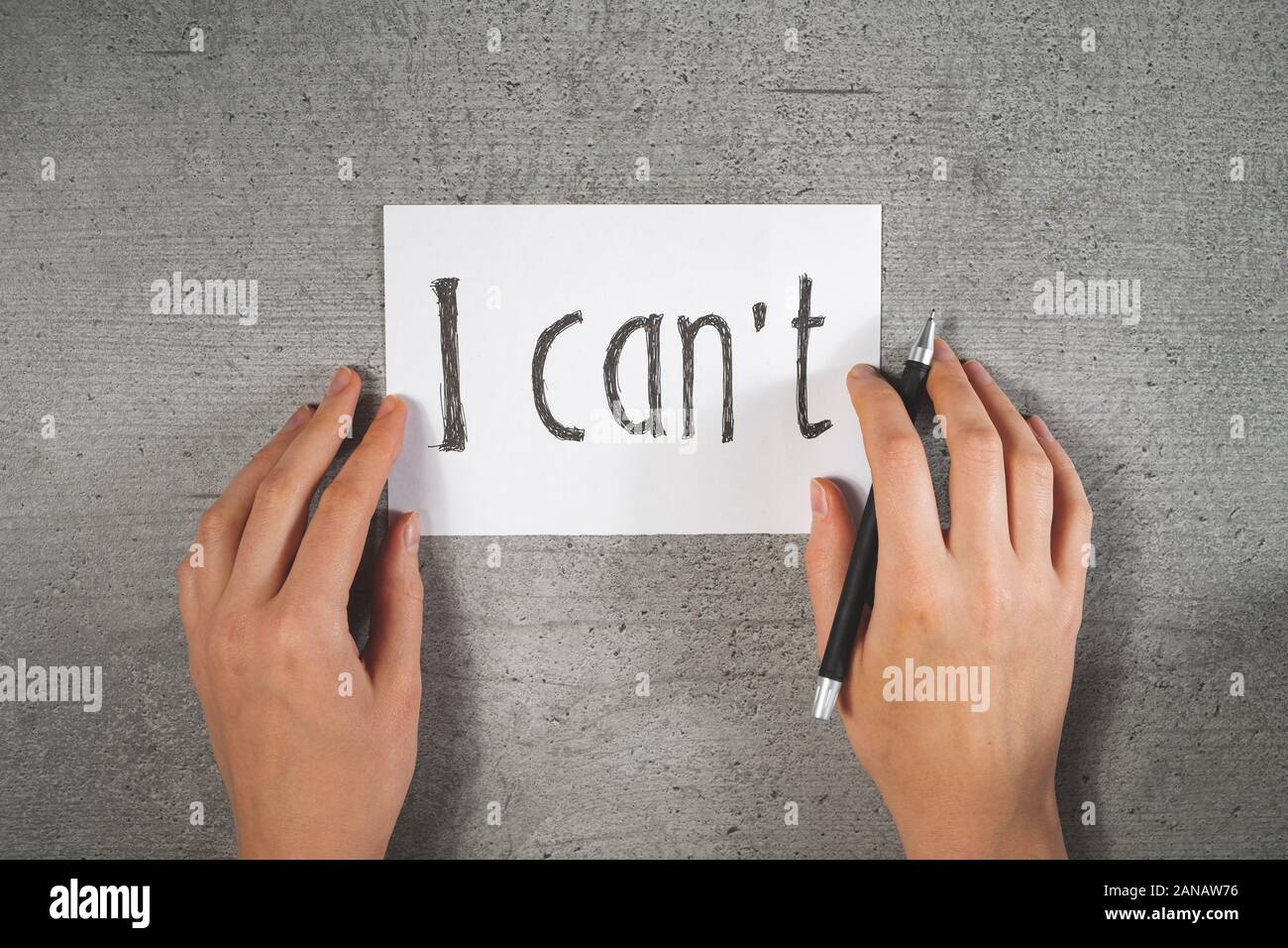 Hands with a pen and sign 'i can't' on the paper. Motivational concept, writing a note, disbelief in yourself or lack of self confidence concept. Stock Photo