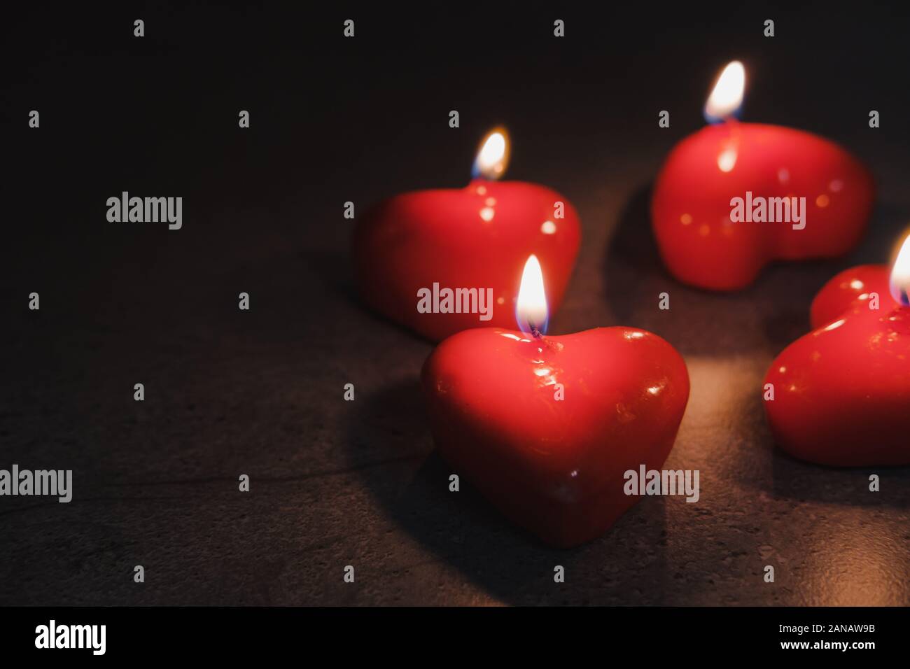 Heart shaped candles burn in the darkness. Concept of the Saint Valentine's Day Stock Photo