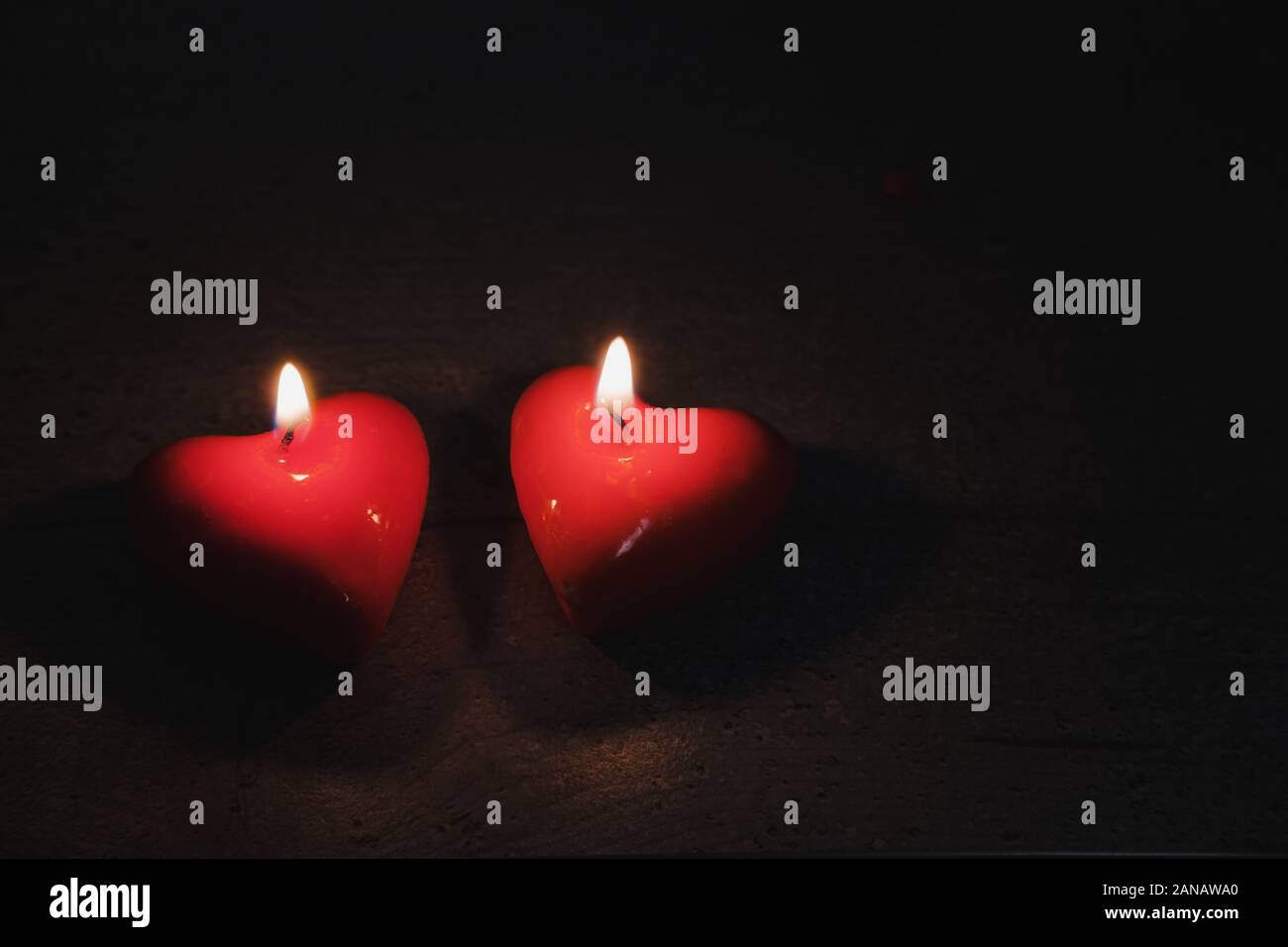 Two heart shaped candles burn in the darkness, copy space. Concept of the Saint Valentine's Day, love and romantics Stock Photo