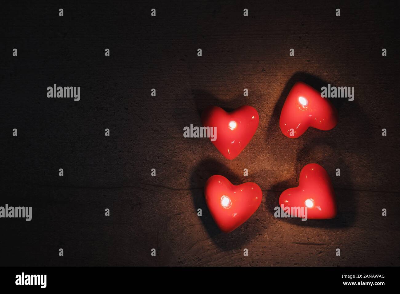 Heart shaped candles burn in the darkness, top view with copy space. Concept of the Saint Valentine's Day Stock Photo