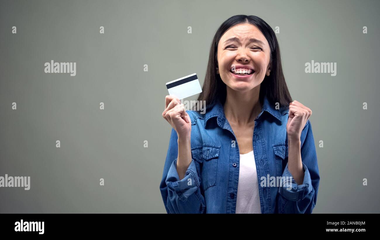 Extremely happy asian woman holding credit card, low interest rate for crediting Stock Photo