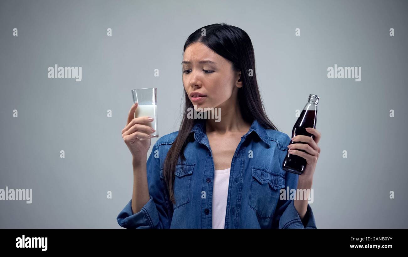 Asian woman choosing between unhealthy carbonated drink and useful healthy milk Stock Photo Alamy