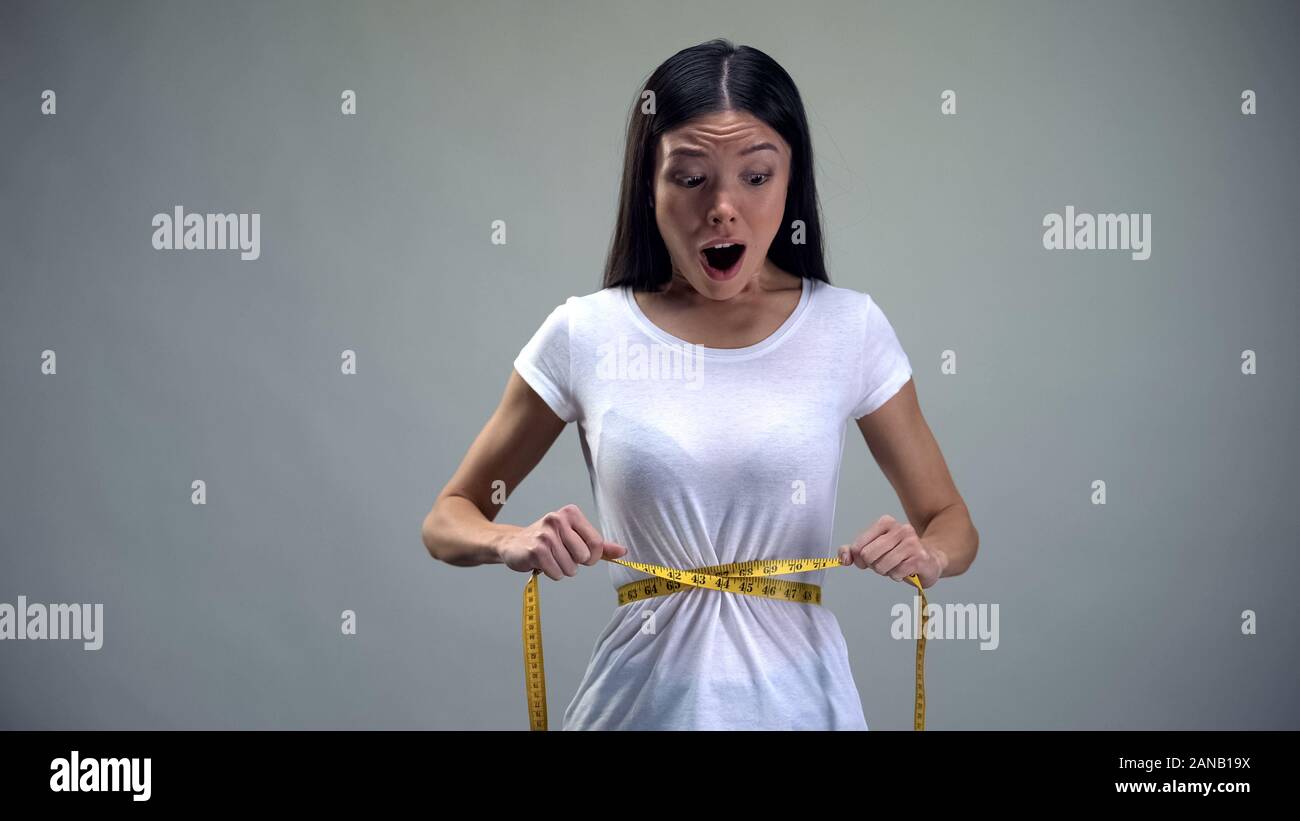 Obsessed woman tightening measuring tape on her waist desire to be slim,  bulimia Stock Photo - Alamy