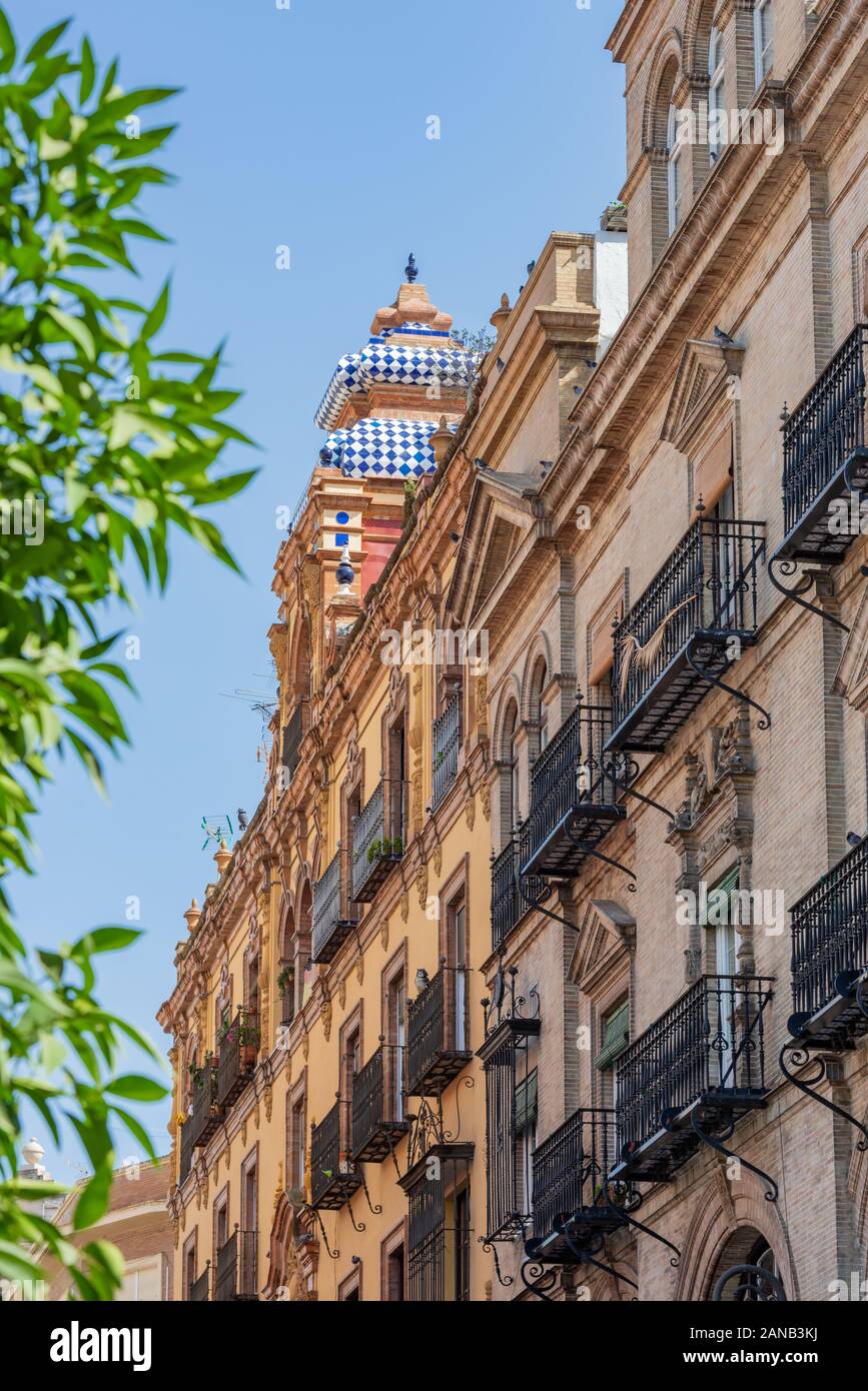 Bright blue and white tiles top a colourful building in Calle Cuesta del Rosario, Seville Stock Photo