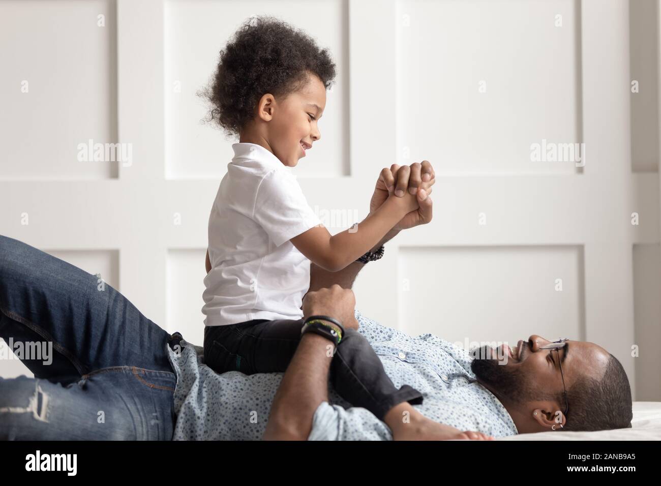 Black man playing with cute son in bedroom. Stock Photo
