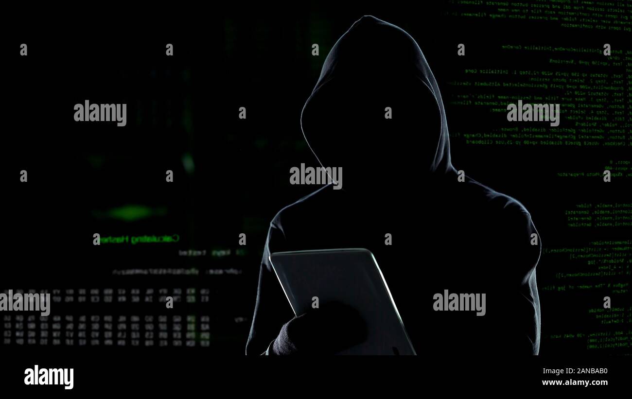 Cyber attack with unrecognizable hooded hacker using tablet computer, cybercrime Stock Photo